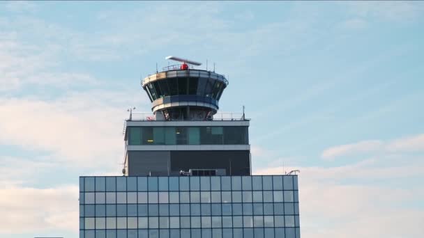 หอควบคุมสนามบินที่มีบูธโปร่งใส โพสต์คําสั่งการขนส่งทางอากาศบนชั้นบนอาคารหลายชั้นพื้นหลังเมฆฟ้าสีฟ้า การควบคุมอากาศยานและแนวคิดการสังเกตการณ์สนามบิน . — วีดีโอสต็อก