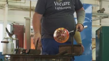 Cam üfleyici bir çubuk üzerinde erimiş cam baloncuğu şekillendiriyor. Cam üretim süreci. Cam şişe ya da vazo üretimi. Profesyonellerden iş akışı.