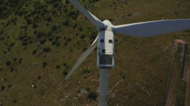 Rüzgâr türbini pervanesini yakınlaştır ve arka planda Krk ve Adriyatik Denizi ile dağlardaki bir rüzgar çiftliğinin hava görüntüsünü aç.