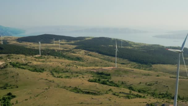 Luftaufnahmen von Windkraftanlagen in den Bergen vor dem Hintergrund der Insel Krk in Kroatien. Erzeugung von grünem Strom — Stockvideo