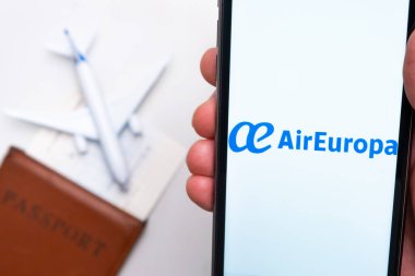 AirEuropa Havayolları uygulaması Man 's Hand' de akıllı telefon ekranında. Oyuncak uçak, pasaport ve biletler masada. Kasım 2021, San Francisco, ABD.