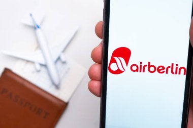 AirBerlin Havayolları uygulaması akıllı telefon ekranında. Oyuncak uçak, pasaport ve biletler masada. Kasım 2021, San Francisco, ABD.