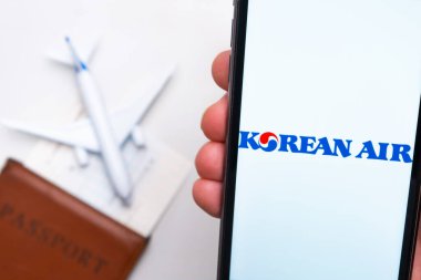 Kore Hava Yolları uygulaması cep telefonunun ekranında. Pasaport, levrek arka planda beyaz bir uçağın yanında. Kasım 2021, San Francisco, ABD.