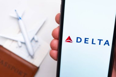 Delta Havayolları uygulaması cep telefonunun ekranında. Pasaport, levrek arka planda beyaz bir uçağın yanında. Kasım 2021, San Francisco, ABD.