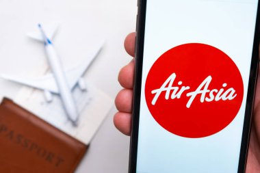 AirAsia Havayolları logosu cep telefonu ekranında, arka planda bir uçak, pasaport ve uçuş kartı var. Havayolları mobil uygulaması kavramı. Kasım 2021, San Francisco, ABD.