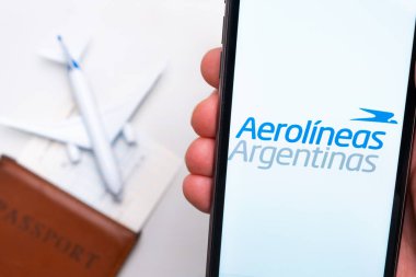 Aerolineas Arjantin Havayolları uygulaması erkek eliyle cep telefonu ekranında. Pasaport, levrek arka planda beyaz bir uçağın yanında. Kasım 2021, San Francisco, ABD.