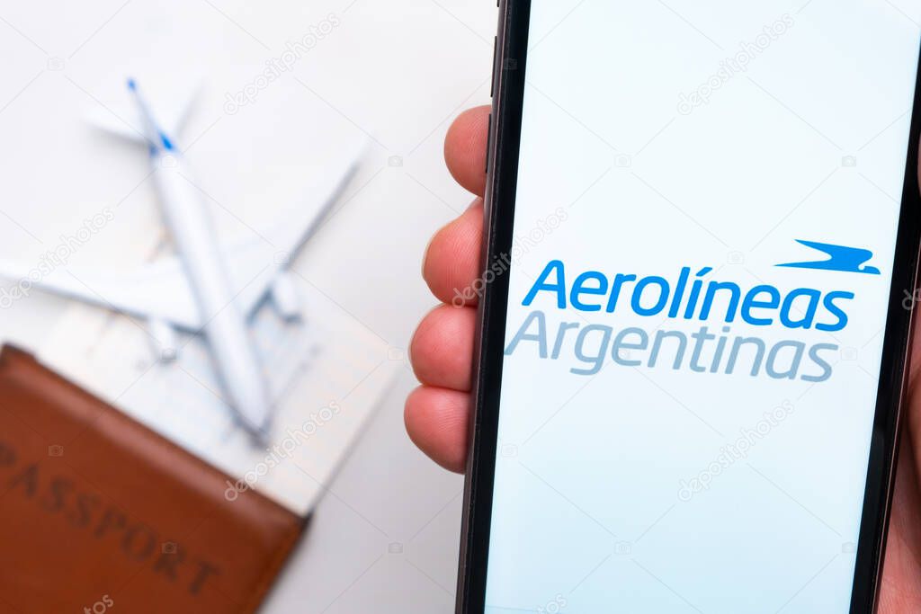 Aerolineas Argentinas Airline application on the screen of mobile phone in mans hand. Passport, boarding bass are next to a white plane on the background. November 2021, San Francisco, USA