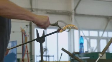 Cam ustası dükkanda maşa kullanarak cam yaprağı yapıyor.
