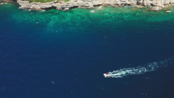 リゾートの険しい崖を過ぎて海に沿ってモーターボートが帆 — ストック動画