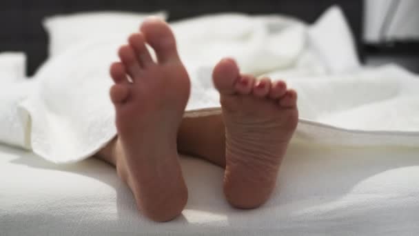 Žena s červenou pedikúrou houpe bosé nohy ležící na posteli — Stock video