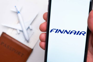 Finnair Havayolları uygulaması akıllı telefon ekranında gösterilir. Arka planda bulanık bir uçak, pasaport ve biniş kartı var. Kasım 2021, San Francisco, ABD.