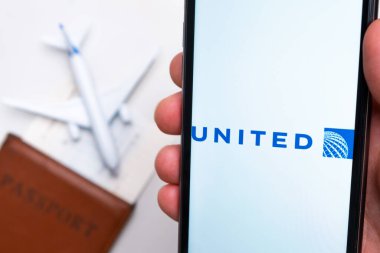United Airlines uygulaması arka planında uçak ve pasaport olan bir akıllı telefon ekranında. Seyahat uygulaması kavramı. Kasım 2021, San Francisco, ABD.