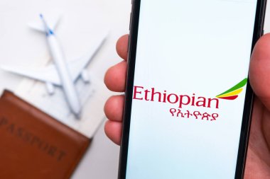 Etiyopya Havayolları uygulaması akıllı telefon ekranında gösteriliyor. Arka planda bulanık bir uçak, pasaport ve biniş kartı var. Kasım 2021, San Francisco, ABD.