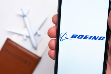 Boeing Havayolları uygulama logosu cep telefonu ekranında. Arka planda bulanık bir uçak görüntüsü, pasaport ve biniş kartı. Kasım 2021, San Francisco, ABD.