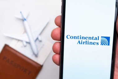 Continental Havayolları uygulama logosu cep telefonu ekranında. Arka planda bulanık bir uçak görüntüsü, pasaport ve biniş kartı. Kasım 2021, San Francisco, ABD.