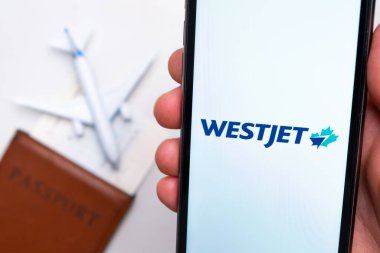 Westjet Havayolları uygulaması arka planda uçak ve pasaport olan bir akıllı telefon ekranında. Seyahat uygulaması kavramı. Kasım 2021, San Francisco, ABD.