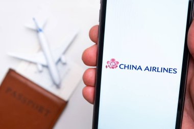 China Airlines uygulamasının logosu cep telefonu ekranında. Arka planda bulanık bir uçak görüntüsü, pasaport ve biniş kartı. Kasım 2021, San Francisco, ABD.