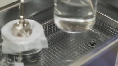 Laboratuar çalışanı, LC MS sistemindeki çözücü ve metal ayrıntı ya da nebulizör iğnesiyle ultrasonik küvete cam bir beher koyar..