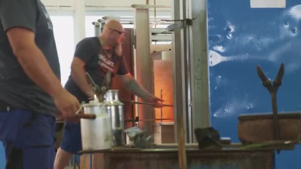 Positiver Mann hebt heißes Glaswerkstück aus Ofen — Stockvideo
