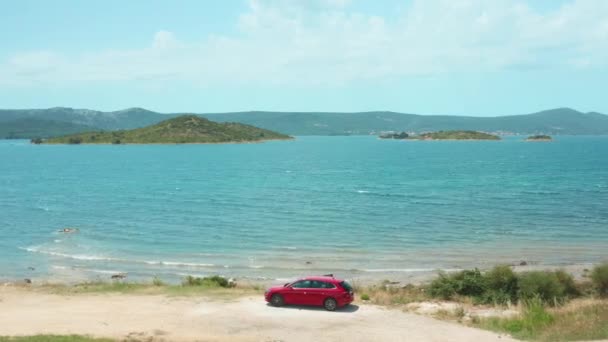 Carro vermelho fica na costa montanhosa da grande baía do mar tranquila — Vídeo de Stock