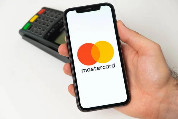 Πληρωμή Mastercard για online αγορές με ασύρματο τερματικό πληρωμών POS στο παρασκήνιο. Άντρας που κρατά κινητό τηλέφωνο με εφαρμογή για πληρωμή. Νοέμβριος 2021, Σαν Φρανσίσκο, ΗΠΑ — Φωτογραφία Αρχείου