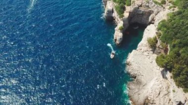 Deniz kıyısındaki kayalıkları aşıp tatil köyüne yelken açar.
