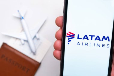 Arka planda uçak, pasaport ve biniş kartı olan cep telefonu ekranında Latam Havayolları logosu var. Havayolları mobil uygulaması kavramı. Kasım 2021, San Francisco, ABD.