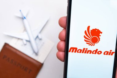 Malindo Havayolları logosu cep telefonu ekranında, arka planda uçak, pasaport ve uçuş kartı var. Havayolları mobil uygulaması kavramı. Kasım 2021, San Francisco, ABD.