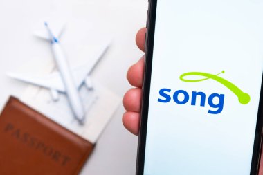 Song Havayolları mobil uygulaması. Arka planda akıllı telefon, pasaport ve uçuş kartı kullanarak bilet almak için uygun bir cep telefonu uygulaması. Kasım 2021, San Francisco, ABD.