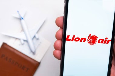 Lion Air Havayolları logosu cep telefonu ekranında, arka planda uçak, pasaport ve uçuş kartı var. Havayolları mobil uygulaması kavramı. Kasım 2021, San Francisco, ABD.