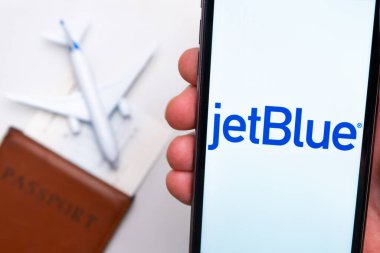 Jet Blue Havayolları uygulaması akıllı telefon ekranında gösteriliyor. Arka planda bulanık bir uçak, pasaport ve biniş kartı var. Kasım 2021, San Francisco, ABD.