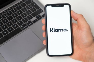 Akıllı telefon kullanarak para transferi için Klarna finans platformu. Ekranda uygulamalı cep telefonu ve arka planda not defteri olan bir adam. Kasım 2021, San Francisco, ABD