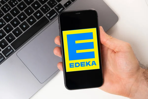 Edeka-Anwendung auf dem Bildschirm von Apple iPhone in der Hand und Laptop im Hintergrund. Online-Shopping-Konzept November 2021, San Francisco, USA — Stockfoto