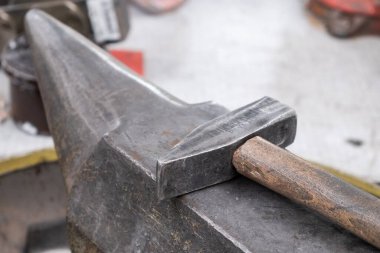 Eski çekiç, Farriery atölyesindeki büyük metal örsün üzerinde yatıyor.