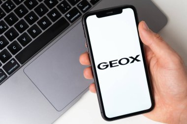iPhone ekranındaki coğrafi uygulama logosu online alışveriş için arka planda bir dizüstü bilgisayarla Kasım 2021, San Francisco, ABD