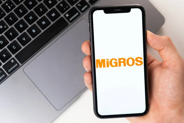 Aplicação móvel MiGROS na tela do smartphone. Um telemóvel na mão de um homem perto de um portátil aberto. novembro de 2021, San Francisco, EUA — Fotografia de Stock