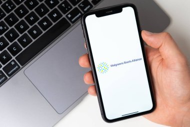 Walgreens Boots Alliance akıllı telefondan başvuru açık. Adam elinde bir cep telefonu tutuyor, şirket başvurusu ekranda açık. Güvenli online alışveriş. Kasım 2021, San