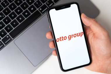 Arka planda dizüstü bilgisayarı olan akıllı telefon ekranında Otto grubu uygulaması. Cep telefonuyla online alışveriş Kasım 2021, San Francisco, ABD