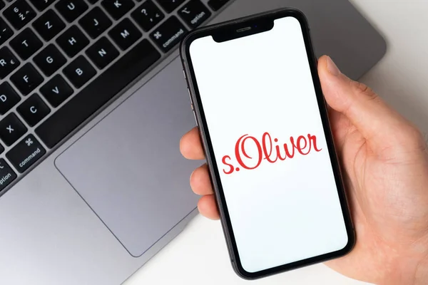 Logotipo de aplicación s.Oliver para compras en línea en la pantalla del teléfono móvil. Hombre de la mano sosteniendo un teléfono inteligente con aplicación Noviembre 2021, San Francisco, EE.UU. — Foto de Stock