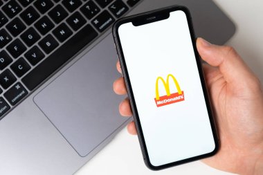 McDonalds akıllı telefondan başvuru açık. Adam elinde bir cep telefonu tutuyor, şirket başvurusu ekranda açık. Güvenli online alışveriş. Kasım 2021, San Francisco, ABD