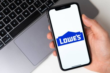 Lowes, akıllı telefonda uygulama açık. Adam elinde bir cep telefonu tutuyor, şirket başvurusu ekranda açık. Güvenli online alışveriş. Kasım 2021, San Francisco, ABD