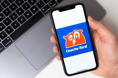 Couche Tard, akıllı telefondan başvuru açık. Adam elinde bir cep telefonu tutuyor, şirket başvurusu ekranda açık. Güvenli online alışveriş. Kasım 2021, San Francisco
