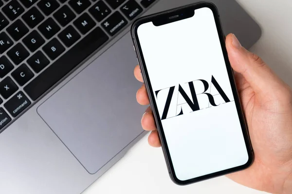 Logotipo de aplicación Zara para compras en línea en la pantalla del teléfono móvil. Hombre de la mano sosteniendo un teléfono inteligente con aplicación Noviembre 2021, San Francisco, EE.UU. — Foto de Stock