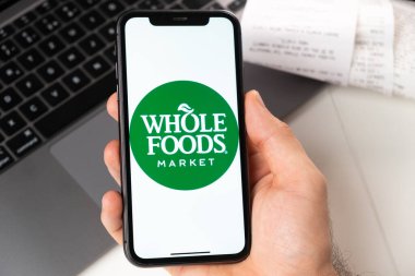 Whole Foods uygulaması Apple iPhone ekranında erkeğin elinde ve arka planda dizüstü bilgisayarı var. Çevrimiçi alışveriş kavramı Kasım 2021, San Francisco, ABD
