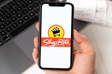 ShopRite application on the screen of Apple iPhone in mans hand and laptop on the background. Online shopping concept November 2021, San Francisco, USA