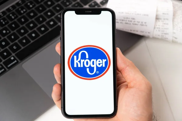 Aplicação Kroger na tela do iPhone da Apple em homens mão e laptop em segundo plano. Conceito de compras on-line novembro 2021, San Francisco, EUA — Fotografia de Stock