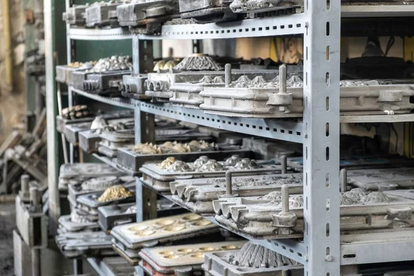 Metal molds for the production of various shapes of glass products lie on the shelves in the factory or glass manufacture — Stockfoto