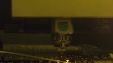 Laser cutter machine cuts thin metal sheet with bright sparks at the manufacture 