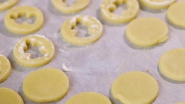 Woman puts round piece of dough on parchment on table