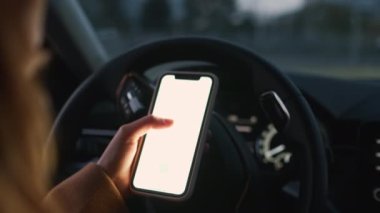 Woman uses mobile phone while driving modern car in city